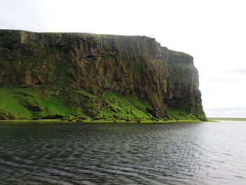 Scenic view of sea by cliff against sky