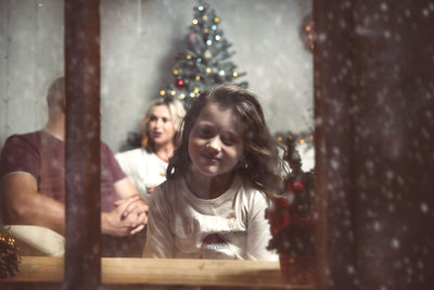 Reflection of girl seen in window during christmas