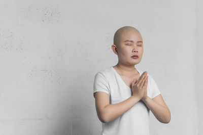 Boy looking away while standing against wall