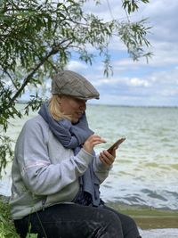 Rear view of women using mobile phone in sea