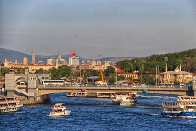 Boats in sea by buildings in city against sky