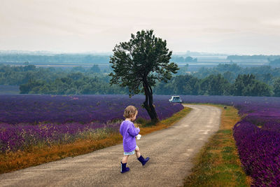 Full length of woman on road amidst field against sky