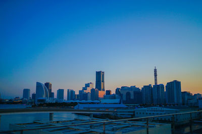 Buildings in city against clear blue sky