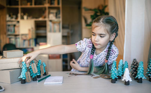 Girl preparing diy gifts and signing tags to family for christmas, handmade, zero waste holidays