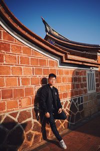 Full length of man standing against brick wall