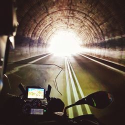Rear view of man photographing illuminated tunnel