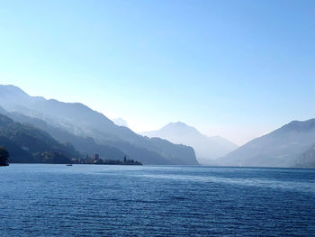 Scenic view of sea and mountains against clear blue sky