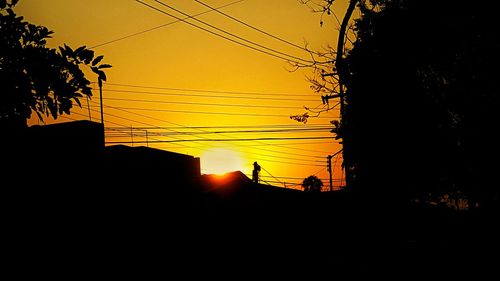 Silhouette electricity pylon against sky during sunset