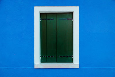 Window with white borders on blue dwelling wall