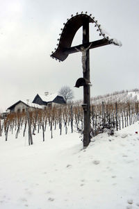 Wooden posts on snow covered field against sky