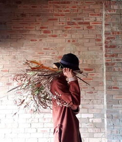 Woman holding umbrella against brick wall