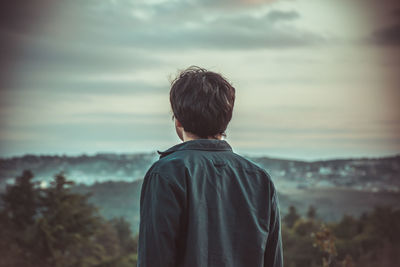 Rear view of man looking at landscape against sky