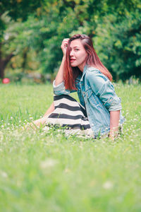 Portrait of beautiful young woman on grass in field