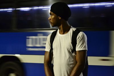 Man standing against bus at night