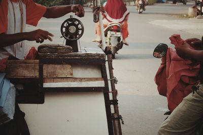 Midsection of tailor with sewing machine by customer on street