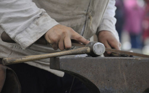 Midsection of man working on metal in workshop