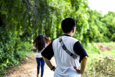 Rear view of man standing on street amidst trees