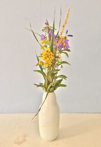 Close-up of flower vase on table against wall