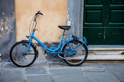 Blue bicycle parked by wall
