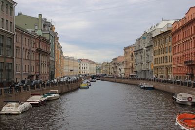 Boats in canal amidst city against sky