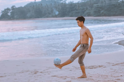 Full length of shirtless man standing on beach