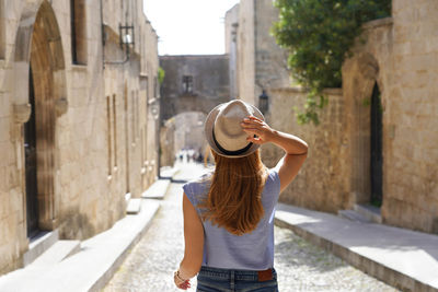 Back view of traveler girl goes down the street of the knights of rhodes city, greece.