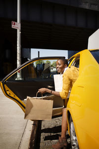 Woman with shopping bags getting out of taxi