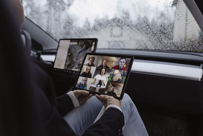 Woman in car holding digital tablet with video conference