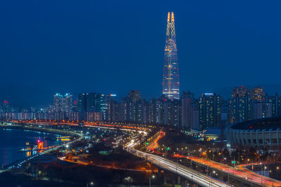 Illuminated buildings in city against blue sky at night