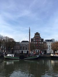 Sailboats moored on river in city against sky