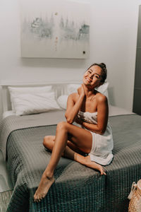 Young woman sitting on bed at home