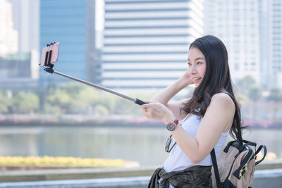Woman with arms raised standing on mobile phone in city