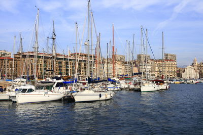 Sailboats moored in harbor against sky