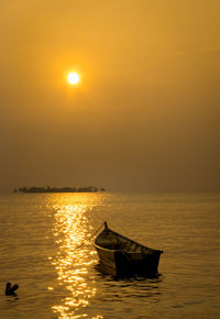 Silhouette boat in sea against sky during sunset