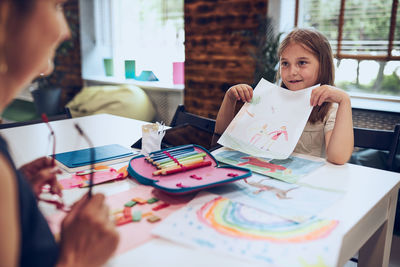 Teacher assisting schoolgirl during art class. child doing homework. primary school. learn and fun