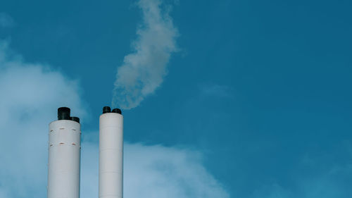 Smoke from chimney set against a blue sky