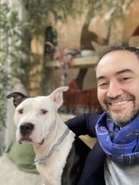 Portrait of smiling man with dog sitting outdoors