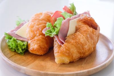 Close-up of croissants and with meat and salad on wooden plate