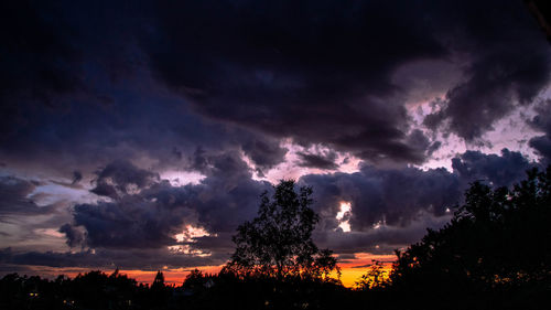 Silhouette trees against dramatic sky during sunset