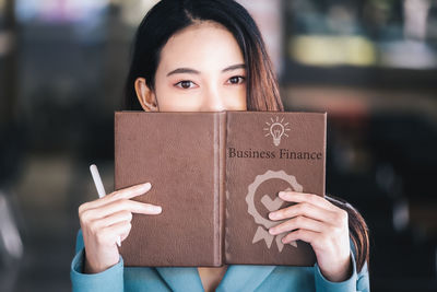 Midsection of woman holding paper while standing in library