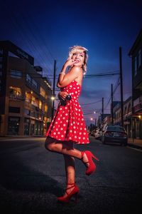 Young woman smiling while standing on street at night