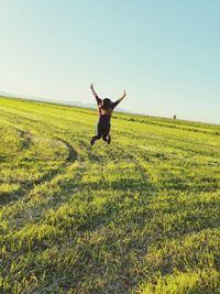 Full length of man jumping on field against clear sky