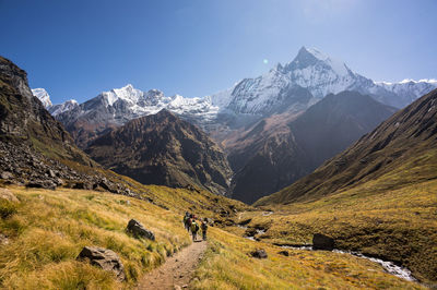 High angle view of people hiking on mountain against clear blue sky during sunny day