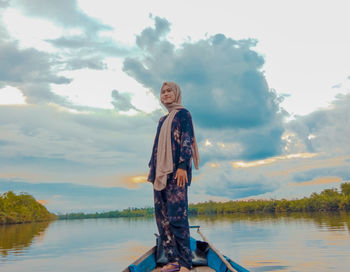 Portrait of smiling standing on lake against sky