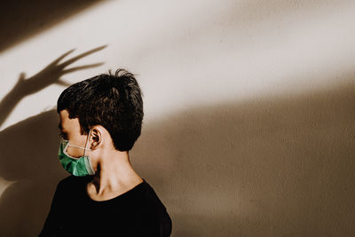 Boy wearing mask standing against wall