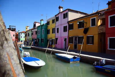 Boats moored in canal against buildings in city