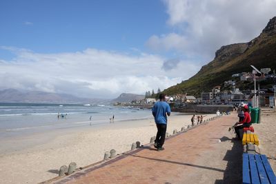 Man on footpath by beach against sky