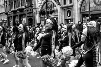 Girls performing with pom-poms on street against building in city