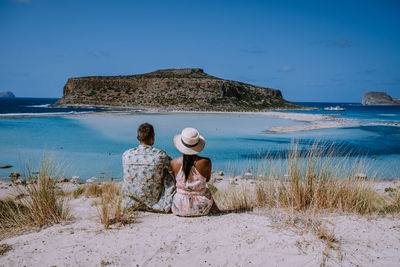 Rear view of friends on beach against sky