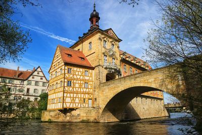 Low angle view of arch bridge over canal amidst buildings against sky